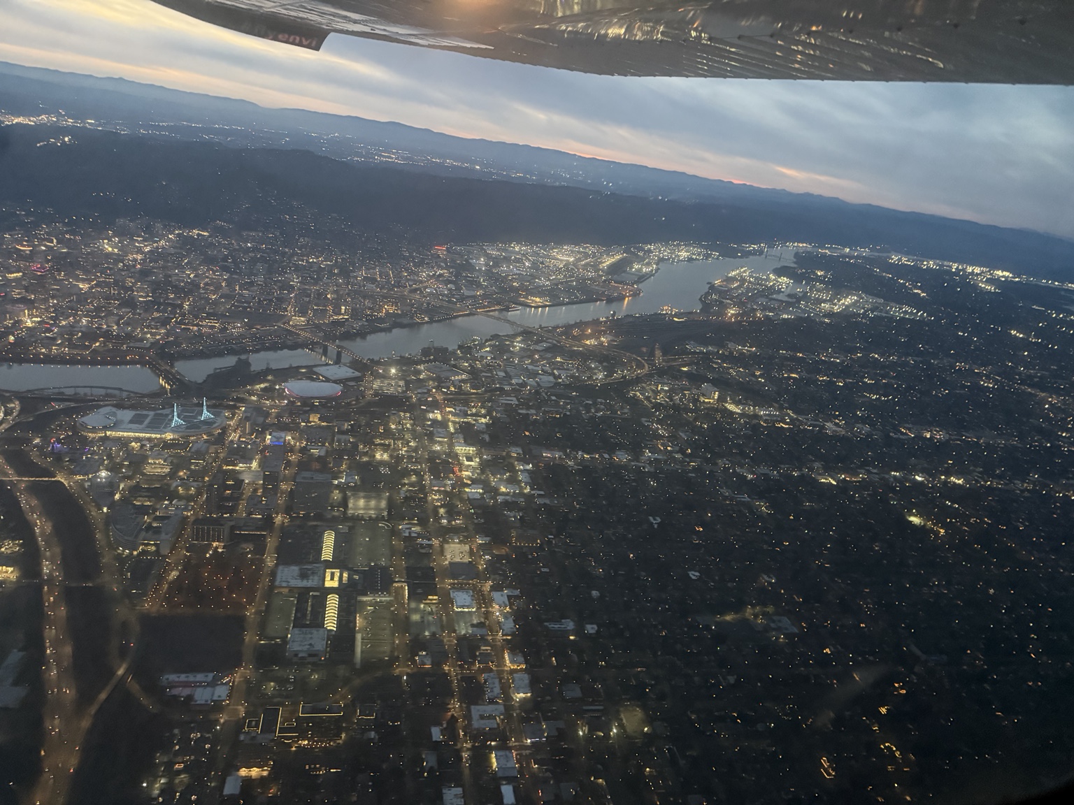 Portland at dusk viewed from an airplane, with the Willamette River, bridges and city lights